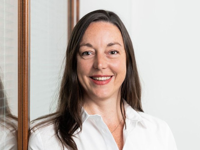 Professional woman wearing a white shirt, smiling confidently 